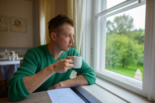 istock Young handsome man relaxing by the window at home 871516354