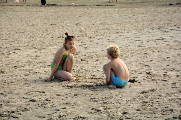 istock Two children sit in the sand on the beach 871516746