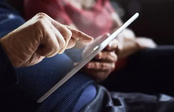 Photo of Senior man's hands tapping tablet screen