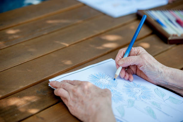 istock Close Up Senior Hands Drawing And Coloring 871518360