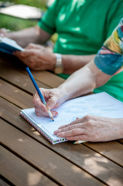 istock Close Up Senior Hands Drawing And Coloring 871518548