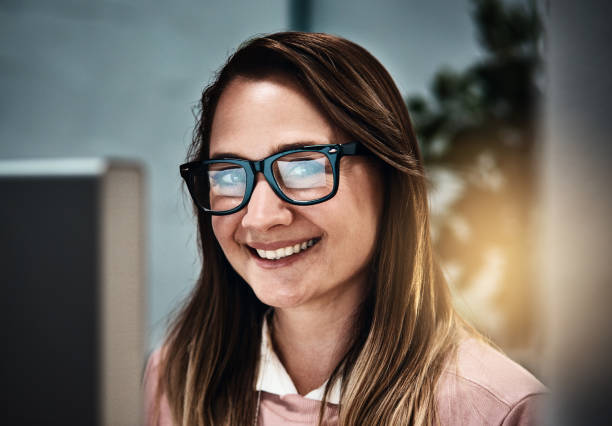istock Woman in spectacles looks up from computer to smile 871521256