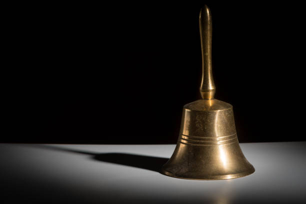 Closeup of a small metallic hand bell Closeup of a small metallic hand bell black background school handbell stock pictures, royalty-free photos & images