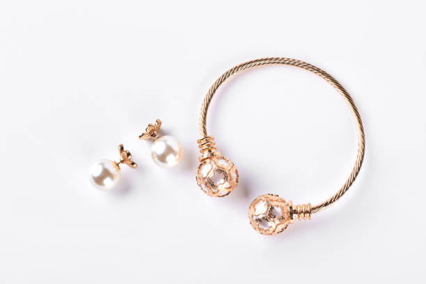 orecchie femminili e bracciale su sfondo bianco. - gold jewelry earring bracelet foto e immagini stock