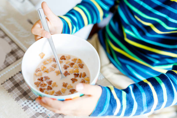 closeup de mãos de garoto garoto comendo cereais caseiros para pequeno-almoço ou almoço - cereais de pequeno almoço - fotografias e filmes do acervo