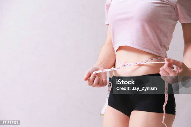 Woman Measuring Her Slim Body Isolated On Background Stock Photo - Download Image Now