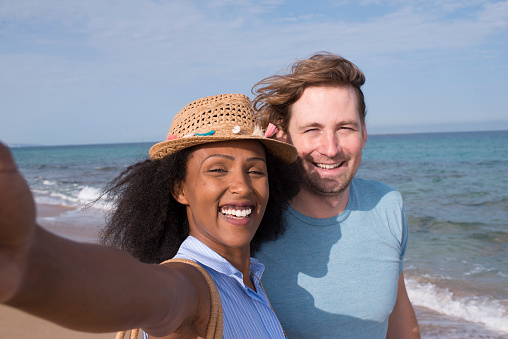 Romantic mixed race couple taking a selfie at the beach.