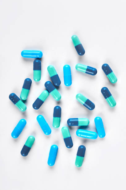 istock Pile of blue capsules on white background. 871540550