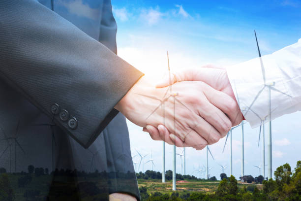 istock Double exposure of handshake with wind turbine. Ecology concept 871543812