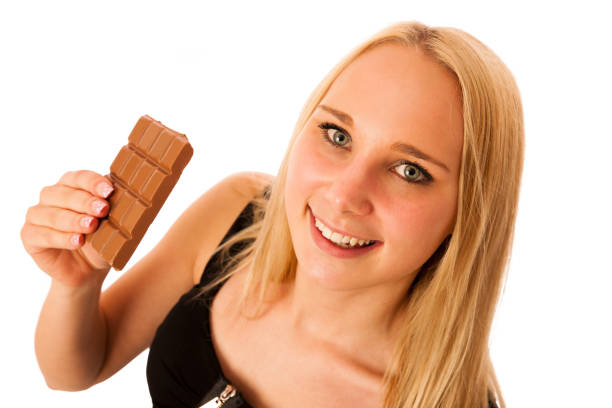istock Beautiful young woman eats chocolate isolated over white background 871544716