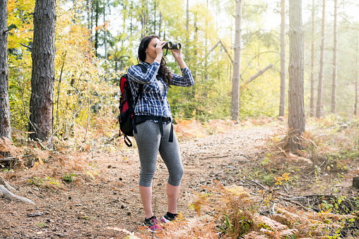 Young female hiker watching through binoculars wild birds