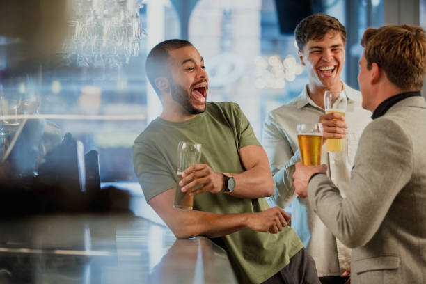 Enjoying Drinks After work Three male friends are enjoying themselves at the bar after work, drinking pints of lager. after work stock pictures, royalty-free photos & images