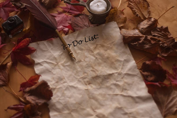 Old to do list paper with feather pen and ink and candle on wooden table stock photo