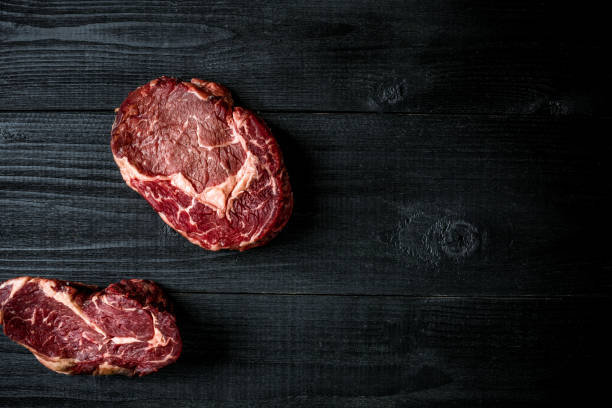istock Fresh raw beef on black wooden background. Top view 871548214
