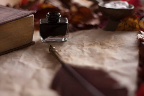 Empty old paper with feather pen and ink, candle and Bible on wooden table