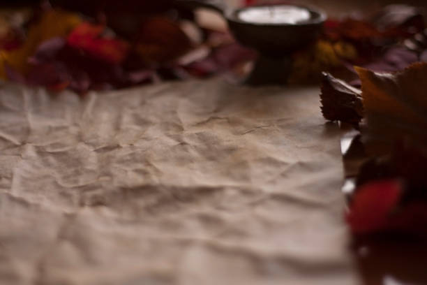 Empty old paper with a candle and leafs on wooden table stock photo