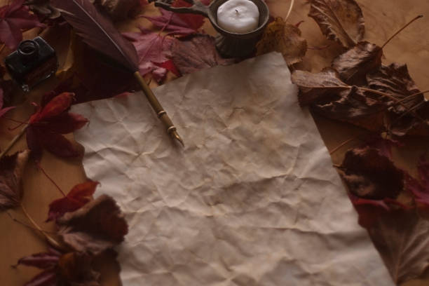 Empty old paper with feather pen and ink and candle on wooden table stock photo