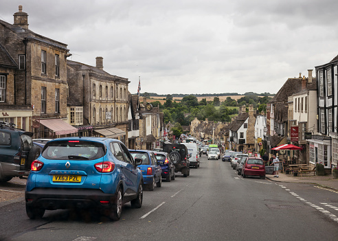 Burford, United Kingdom - Traffic on the main street through the historic village of Burford in the Cotswolds.
