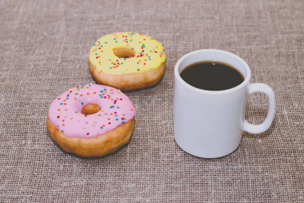 istock Donuts with icing on the table. Nearby is a mug with coffee 871553384