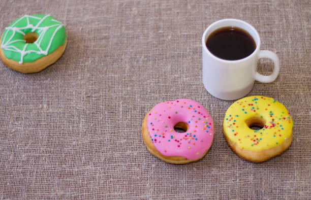 istock Donuts with icing on the table. Nearby is a mug with coffee. Sweet colored donuts 871553646