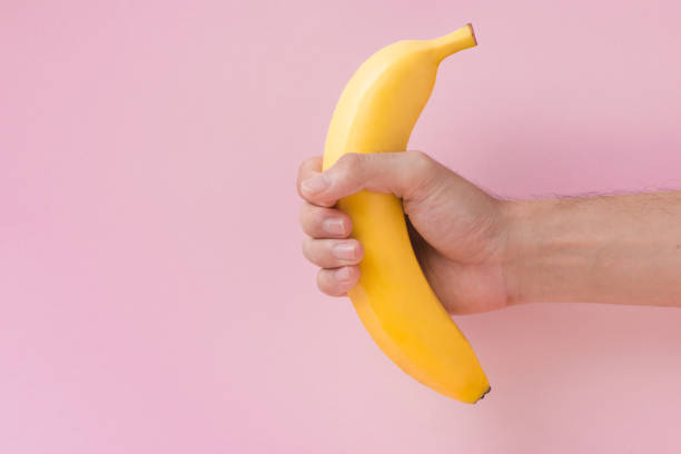 mano maschile che tiene una banana isolata su sfondo rosa. - men banana holding cut out foto e immagini stock