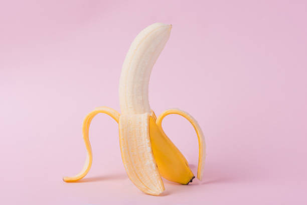 istock Fresh peeled banana on pink background 871554434