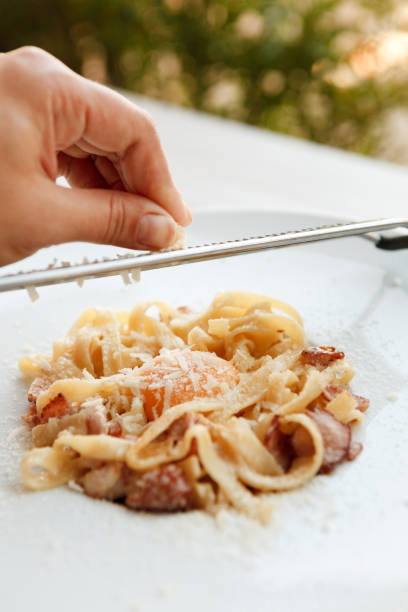 istock Grate parmesan on traditional italian pasta carbonara with bacon and egg 871555176
