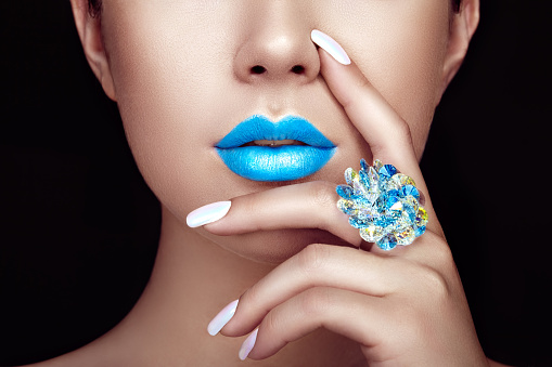 Beauty Fashion woman lips with natural Makeup and white Nail polish. Gloss Blue Lipstick. Beauty girl face close up. Sexy Lips, Manicure, Make up. Ring with Precious Stones, Jewelry