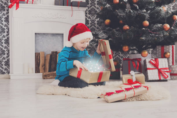 istock Cute happy boy in santa hat unwrapping christmas presents 871564420