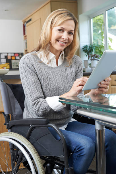 istock Disabled Woman In Wheelchair Using Digital Tablet At Home 871564866
