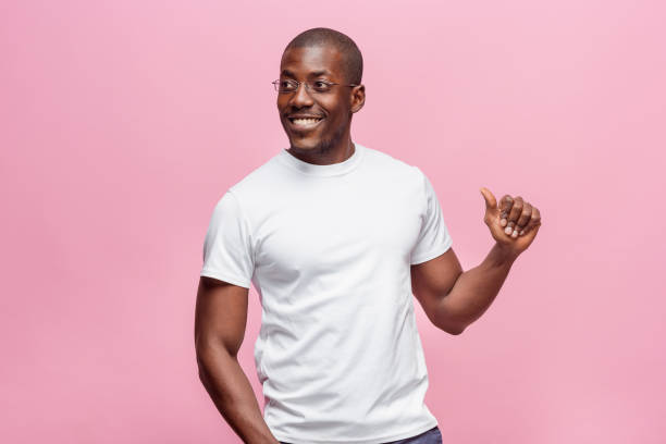 Portrait of a very happy afro American man Portrait of a very happy afro american man showing thumbs up in studio on pink background black man stock pictures, royalty-free photos & images