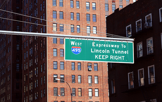 Street sign for West 495 Expressway to Lincoln Tunnel hangs above road in New York City