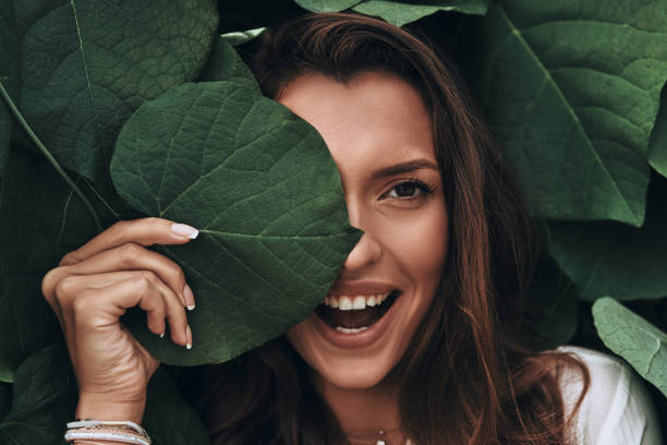 Natural beauty. Attractive young woman looking at camera and smiling while standing among the leaves outdoors natural beauty people stock pictures, royalty-free photos & images
