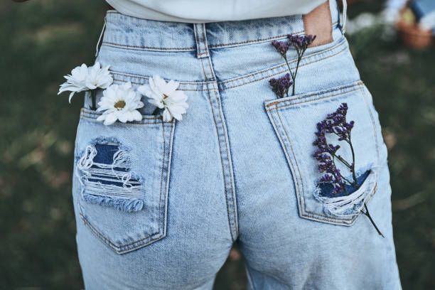 Spring style. Close-up rear view of woman keeping chamomile and lavender in back pockets of her blue jeans while standing outdoors german chamomile nature plant chamomile plant stock pictures, royalty-free photos & images