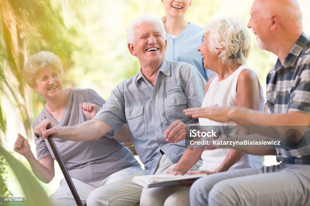 Group of smiling senior friends Group of smiling senior friends enjoying time while sitting together in park Senior Adult Stock Photo