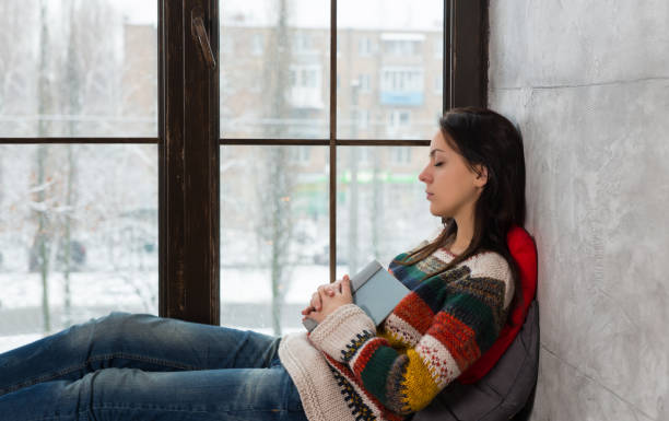 istock Young beautiful woman fall asleep on the windowsill while reading a book 871577894