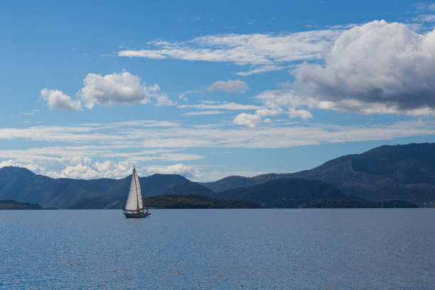 istock one sailing boat on water with lefkas shore mountains and clouds blue sky 871581346