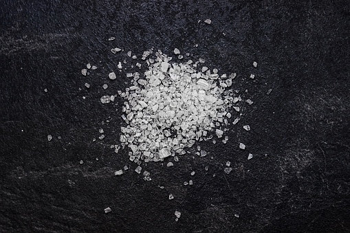Sea salt on a black  stone  background. Ingredients for cooking.