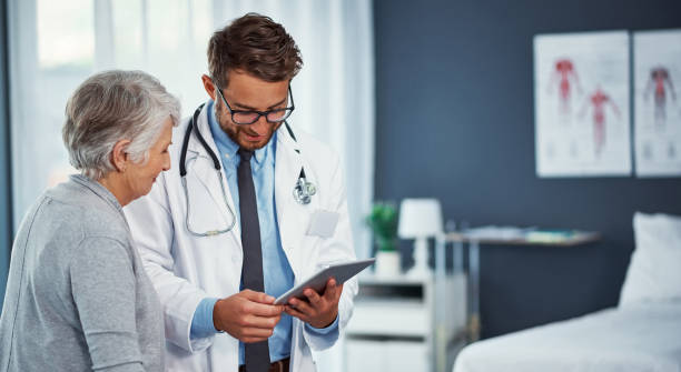 Your health has been improving quite well Shot of a doctor discussing something on a digital tablet with a senior patient in a clinic doctor lifestyle stock pictures, royalty-free photos & images