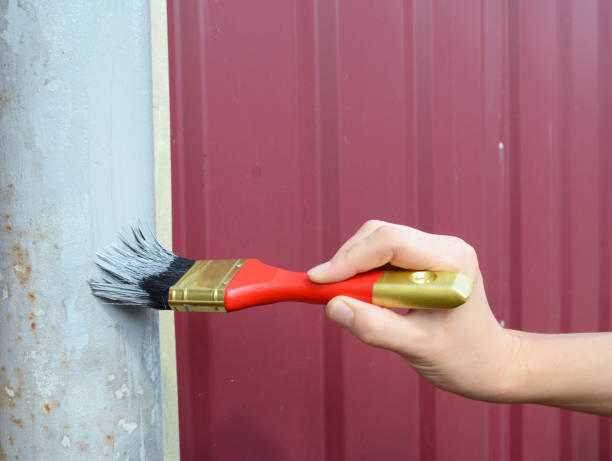 istock Painting metal fence with worker hand. 871585374