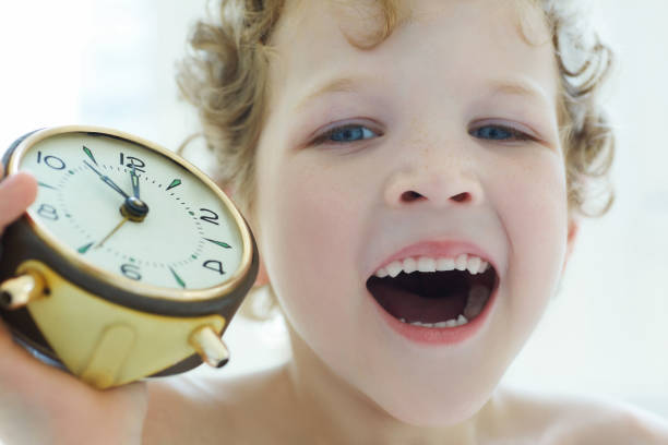 boy yawns holding an antique clock. - clock clock hand antique clock face imagens e fotografias de stock