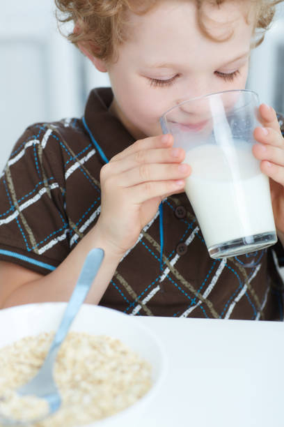 istock Closeup boy drinking milk and smiling while having breakfast  in the kitchen. 871585458