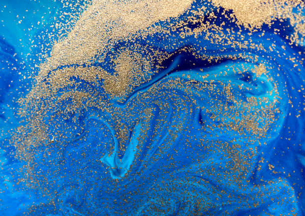 Marbled blue abstract background with golden sequins. Liquid marble ink pattern.