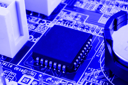 Integrated semiconductor microchip on blue circuit board representative of the high tech industry and computer science.