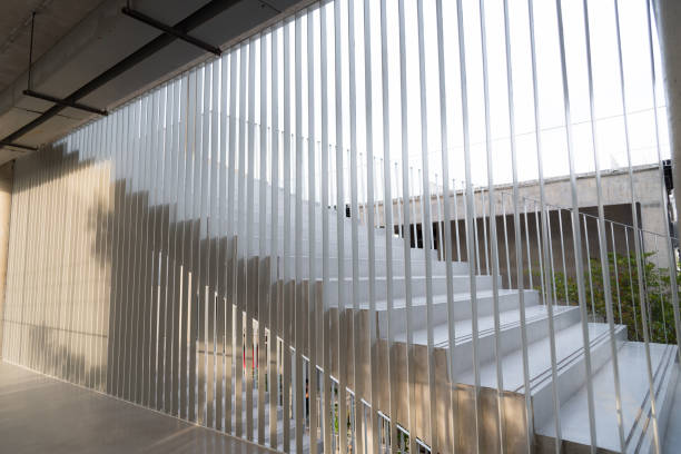 istock Light and shadows of white iron bar projected onto the white stairway. 871605870