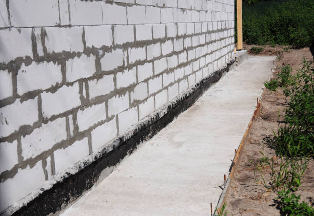 istock Waterproofing and insulation unfinished house foundation wall. Waterproofing house foundation with bitumen membrane. 871606200