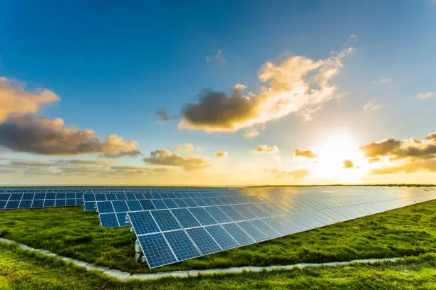 Solar panels at sunrise with cloudy sky in Normandy, France. Solar energy, modern electric power production technology, renewable energy concept. Environmentally friendly electricity production.