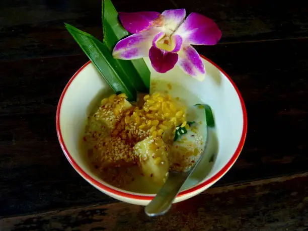 thai dessert with banana and coconutmilk in bowl decorated with orchid