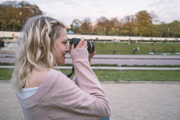istock Young woman photographing Paris using digital camera 871618772