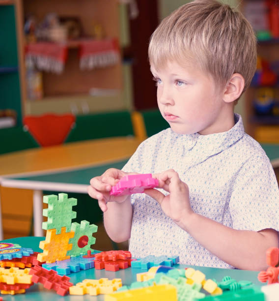 istock Little  cute boy plays with constructor next to the mountain of colored details. 871624784